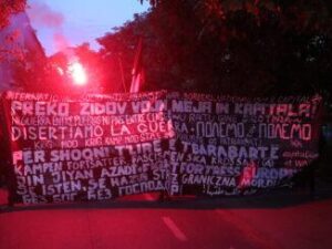 Banderole en tête d'une manifestation organisée pendant la Foire du Livre Anarchiste avec des slogans dans beaucoup de langues différentes. L'un d'eux est "Pas de guerre entre les peuples, pas de paix entre les classes".