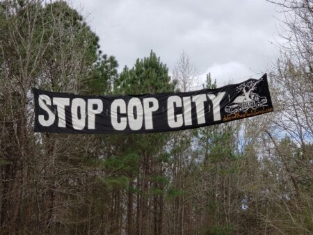 Photo d'une banderole avec le slogan "Stop Cop City" dans la forêt de Weelaney 
