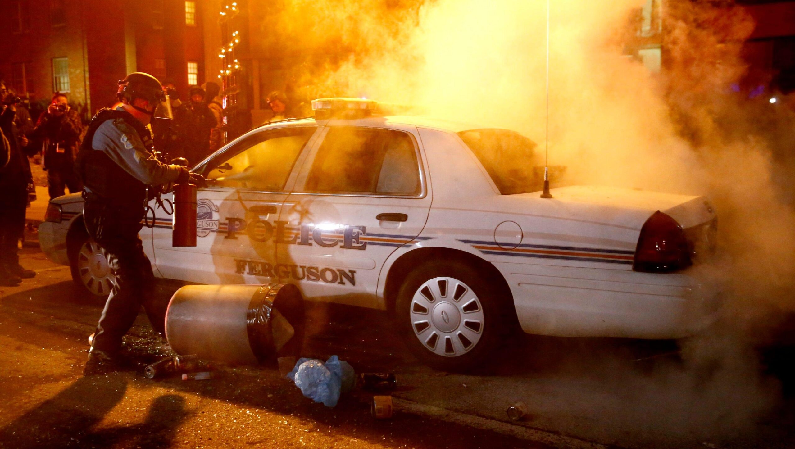 torched police car being extinguished during Ferguson riots